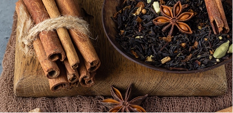 Cinnamon sticks, star anise, and warming whole spices arranged on a dark wooden board for autumn and winter cafe menus